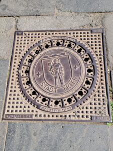 A manhole cover with a man on it holding a giant key. Below it says Stadt Trier