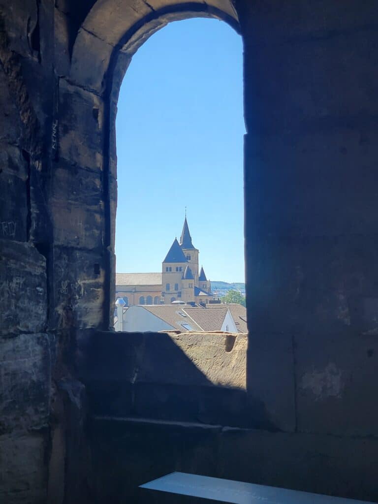 A view of cathedral spires out of a small rounded window in a stone wall