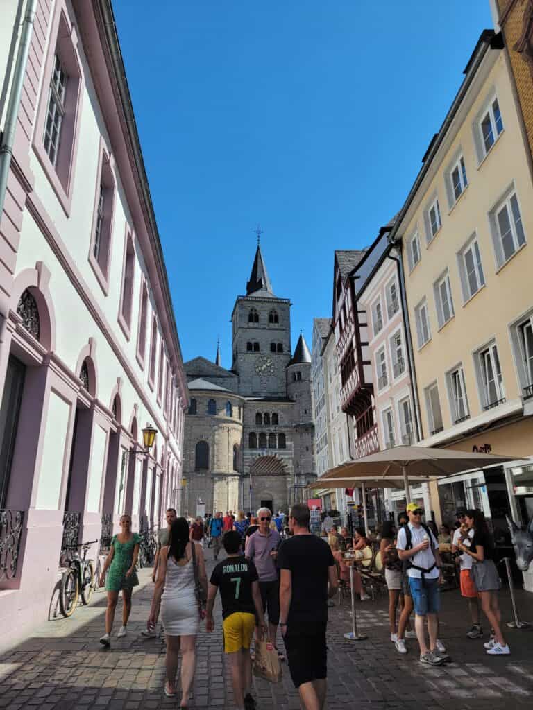 A cobblestone street and people with the Trier cathedral in the background