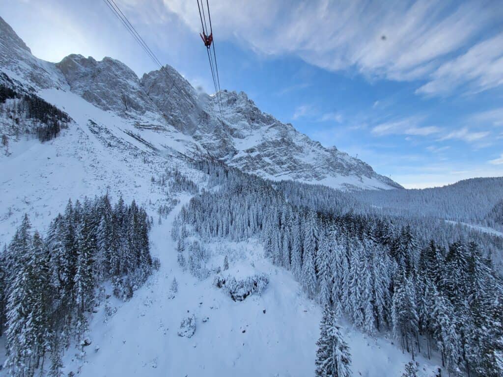 View down the length of the cable used by the Zugspitze cable car with snowy mountains and trees