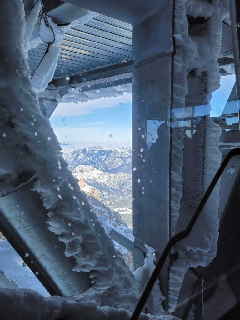 View of snowy mountains between metal beams of the Zugspitze cable car docking station