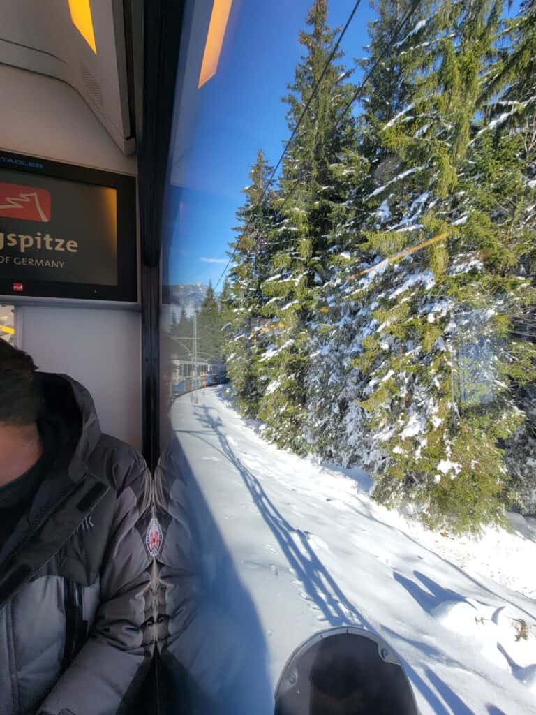 A view along the side of the Zugspitze cogwheel train showing evergeens in the snow