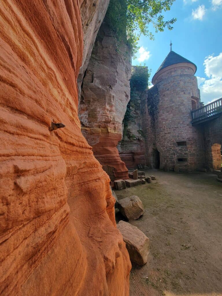 This image shows one of the stone towers of Nanstein Castle and the red sandstone cliff into which the castle was built.