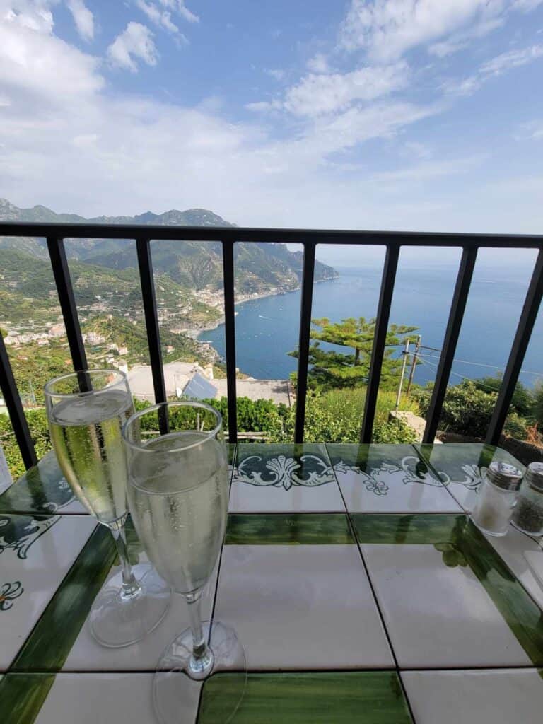 Two champagne glasses and a view overlooking the ocean from a balcony at Villa Amore Ravello