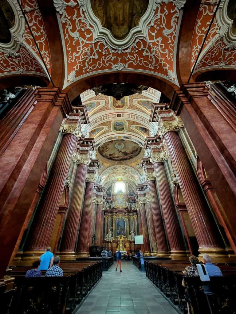 The inside of the magnificent Faro Church with stone floors and large red marble columns leading to the altar