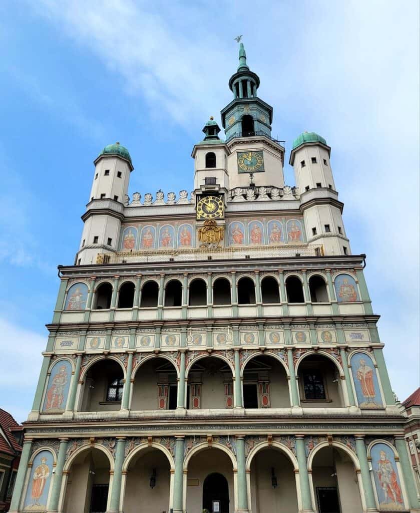 A four-leveled Renaissance bulding with multiple arches on each level, a large tower in the back and three smaller ones in the front. The center has a clock underneath.