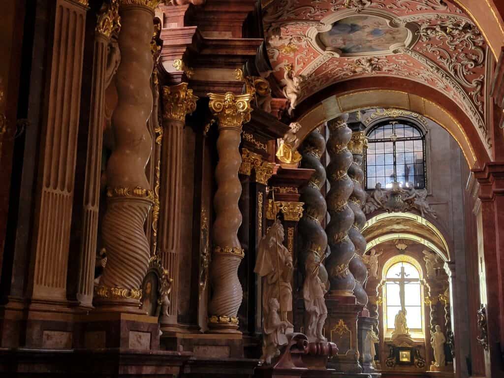 A row of intricate swirling columns made of colored marble, and a window at the end