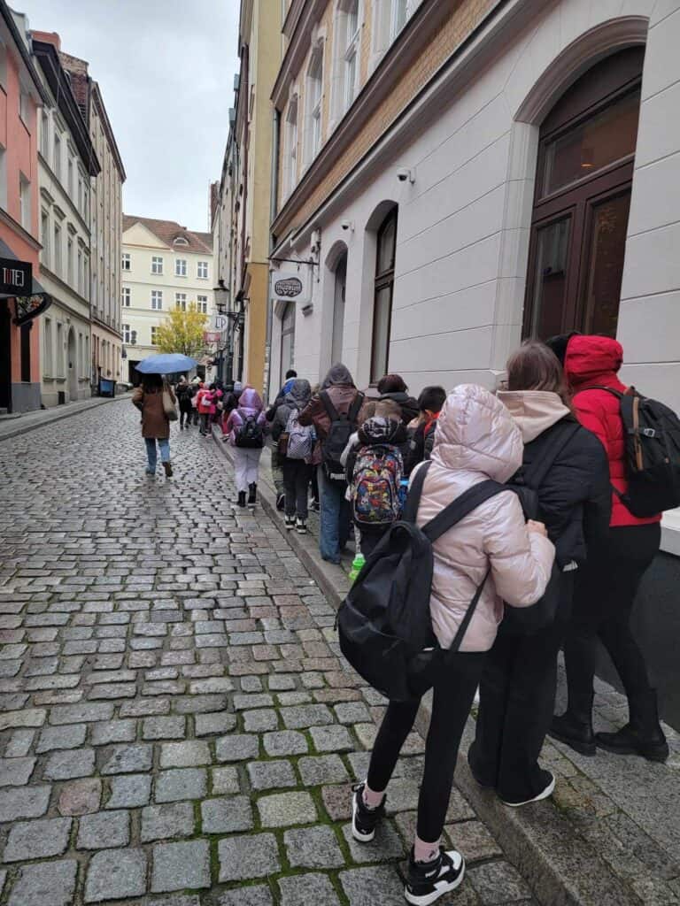 A line of children on a cobblestone street waiting to enter the museum