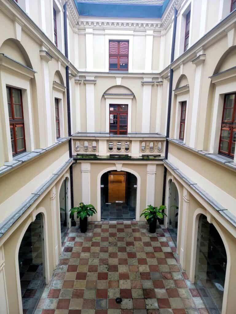 A courtyard with red and white tiled floor and three levels of white walls with windows