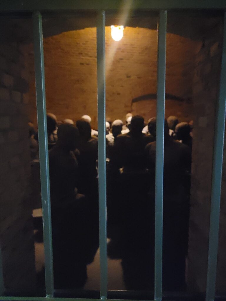 Dark faceless mannequins in a cell with bars in front