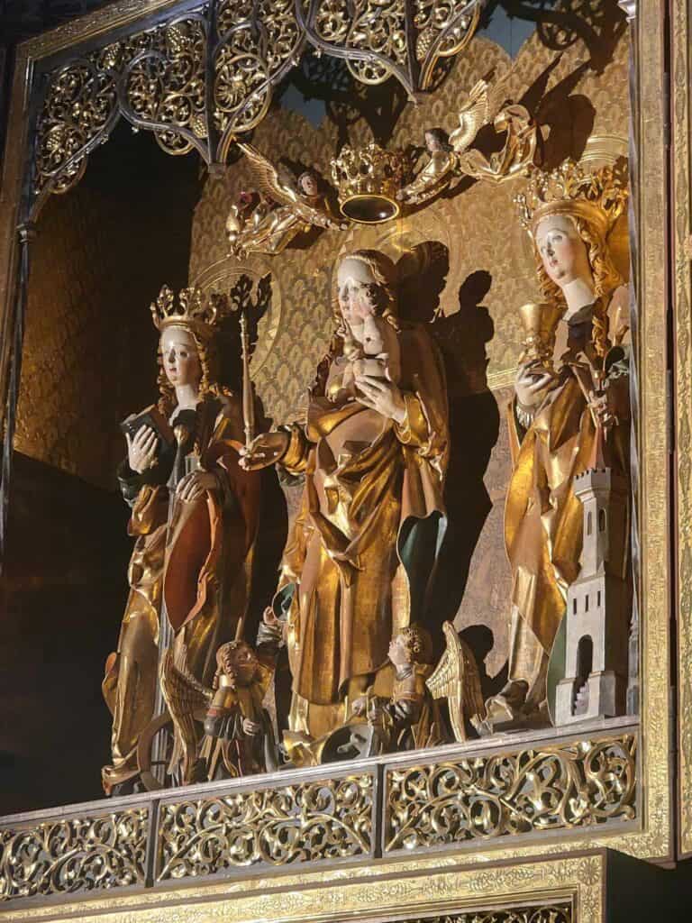 Wooden medieval gilded carving of three female saints in robes with crowns