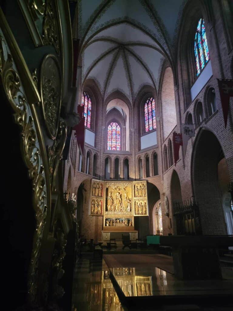 The altar and high arched ceiling of the Poznan cathedral with stained glass and a golden triptych altarpiece