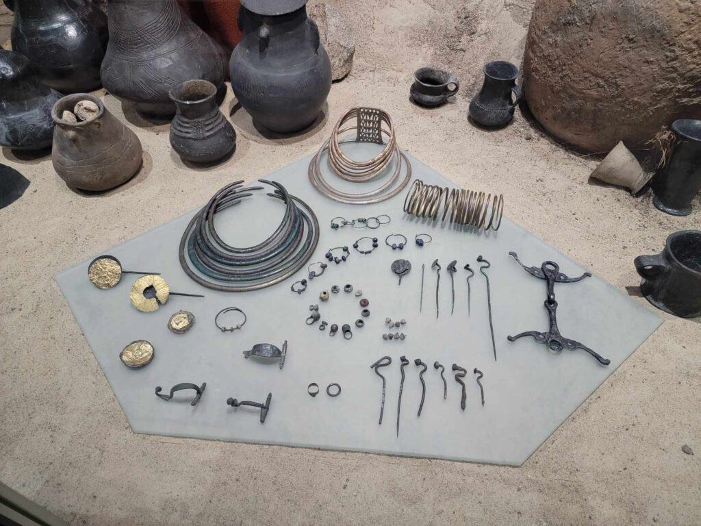 A display of Polish artifacts including pins, bracelets, necklaces, and pots