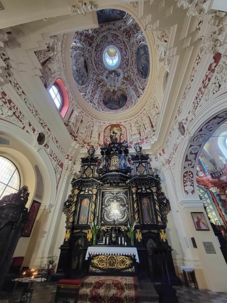 An incredibly detailed and ornate baroque interior in white, and an elaborate black and gold altar