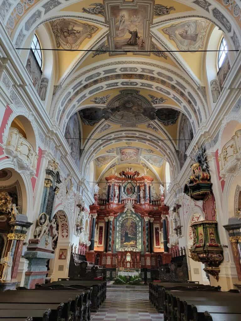 Looking down the aisle of the Yellow Church with dark wooden pews on either side and an intricate baroque altar in red and yellow