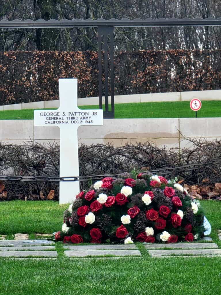 The grave of Gen. Patton marked with a white cross and red roses