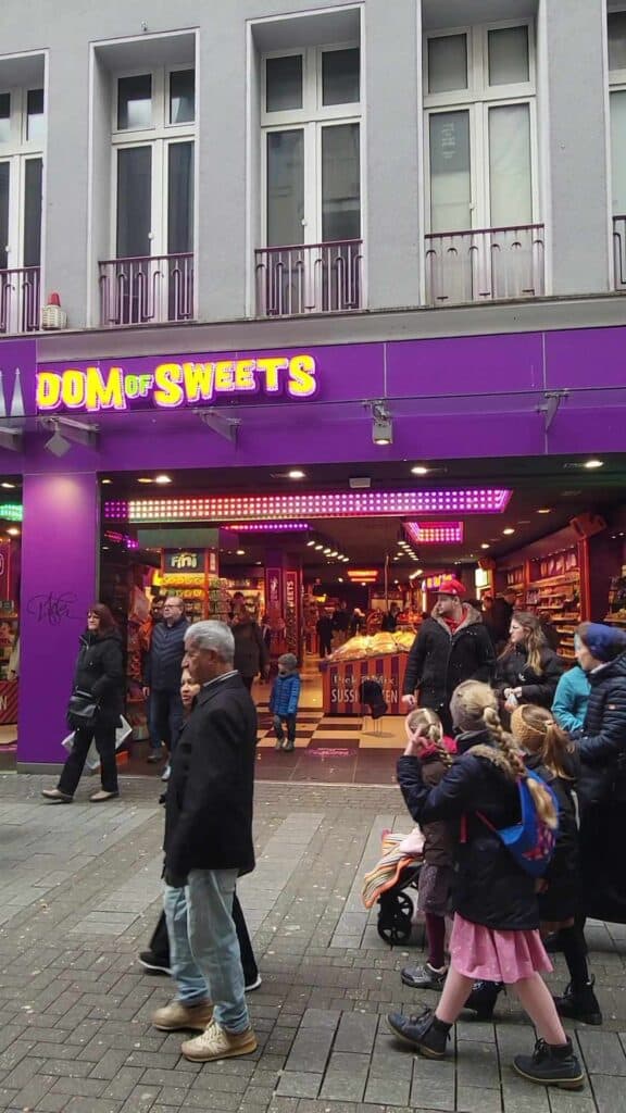 A candy store in Cologne Germany with a bright purple facade. Sign reads Dom of Sweets