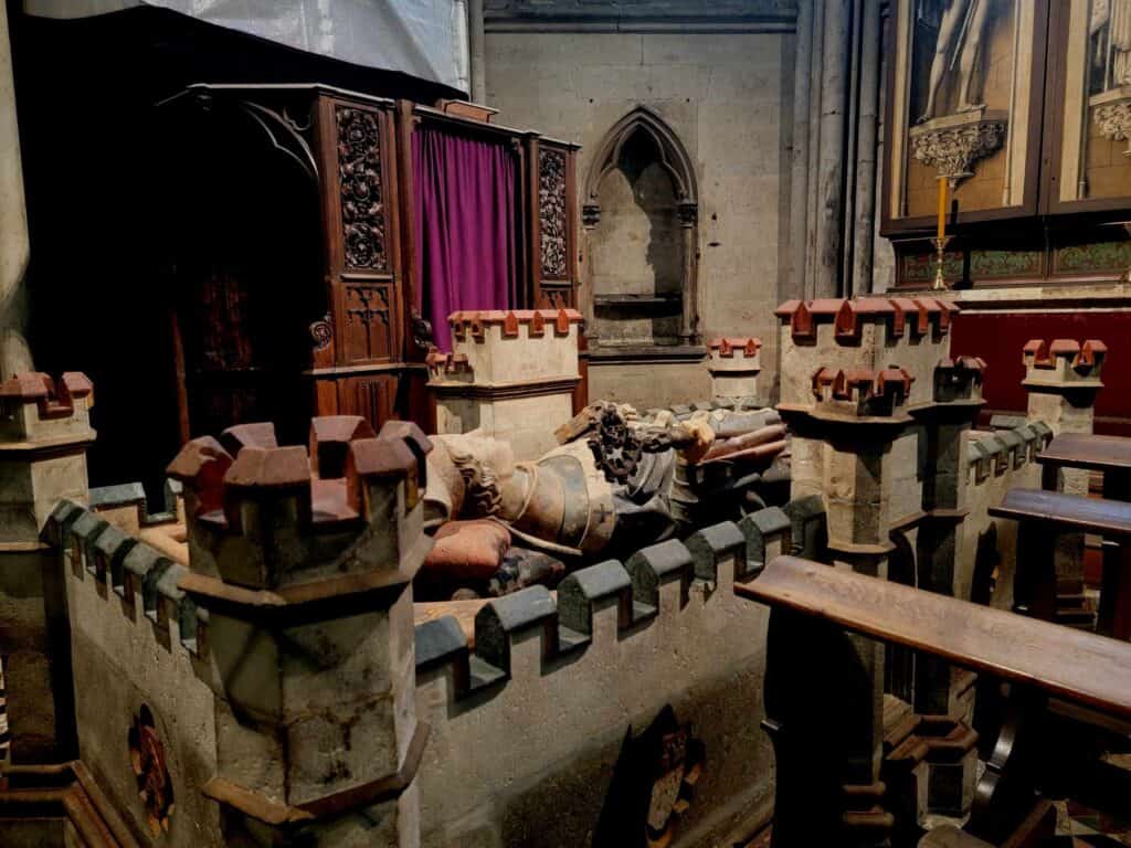 A chapel showing the tomb of a noble person who appears to be sleeping on castle ramparts