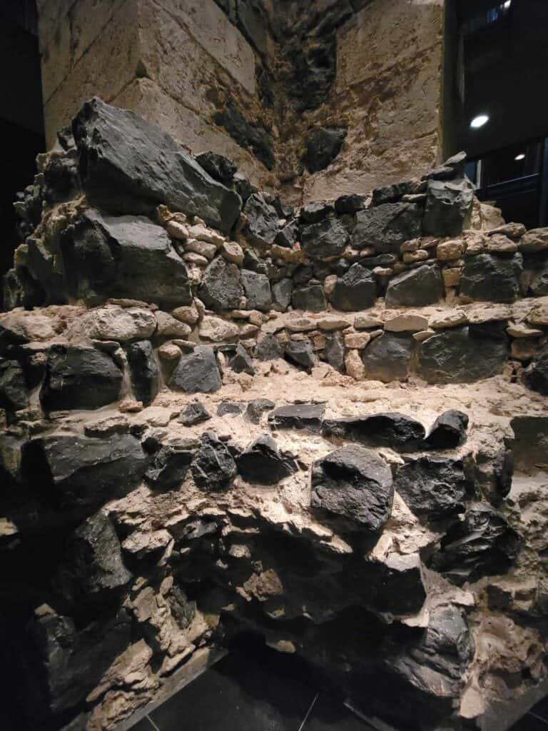 A piece of the old Roman wall  in Cologne Cathedral's treasury that looks like a crumbling pile of dark stones and pale mortar