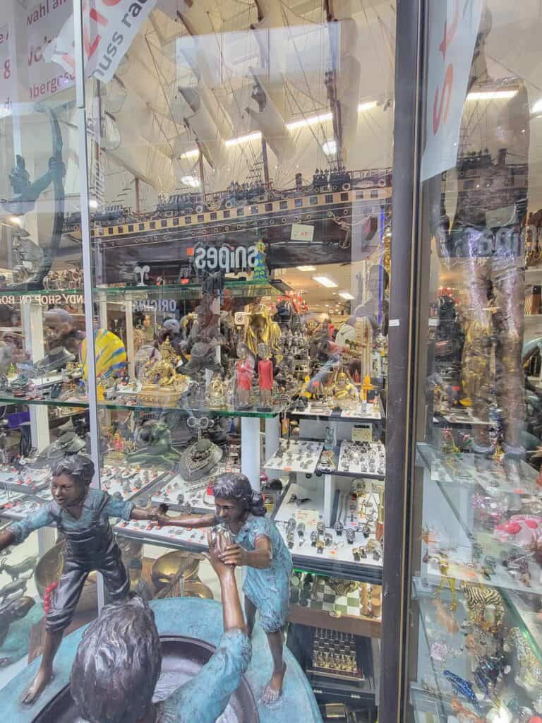 A store window of an antique store filled with bronze sculptures and antiques in Cologne