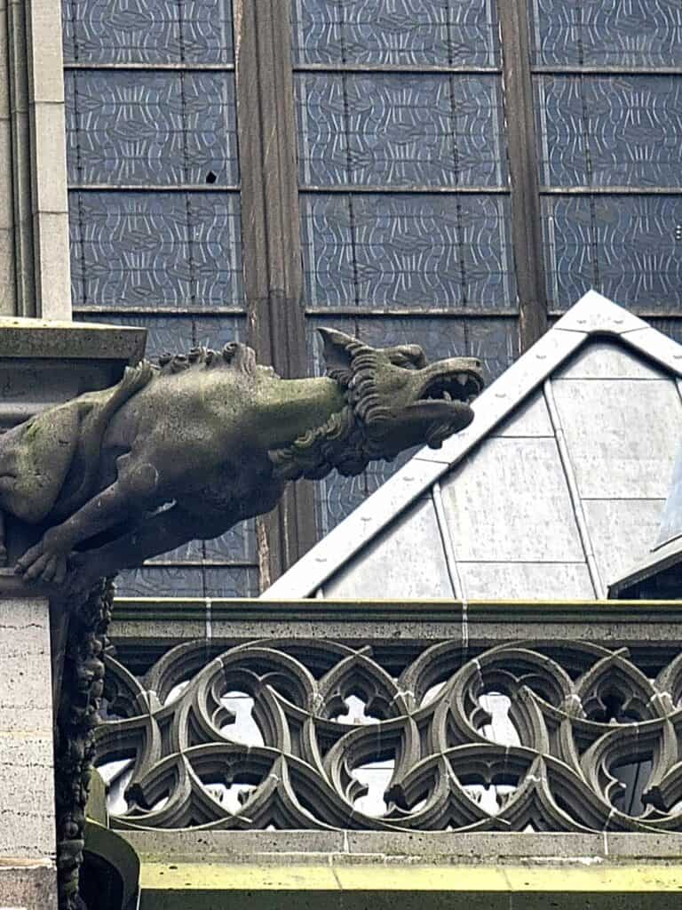 A horned gargoyle on Cologne Cathedral stretching out over the street