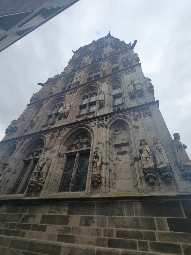 The facade of a building in stone with religious sculptures on either side of arched windows