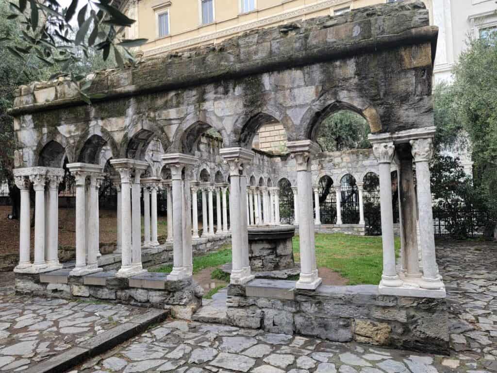 A small green courtyard surrounded by white stone pillars and arches