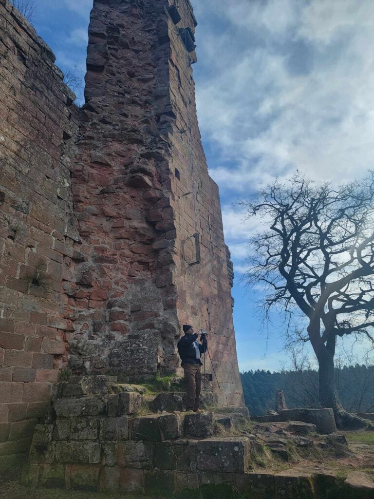 A man stands at the base of a large thick defensive wall at Hohenecker Castle in Kaiserslautern Germany