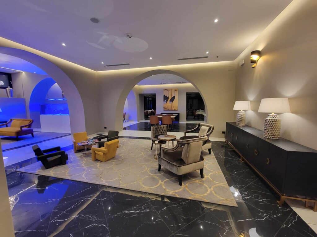 A hotel lobby with white arched walls, grey velvet furnisture and a credenza with cream colored lamps