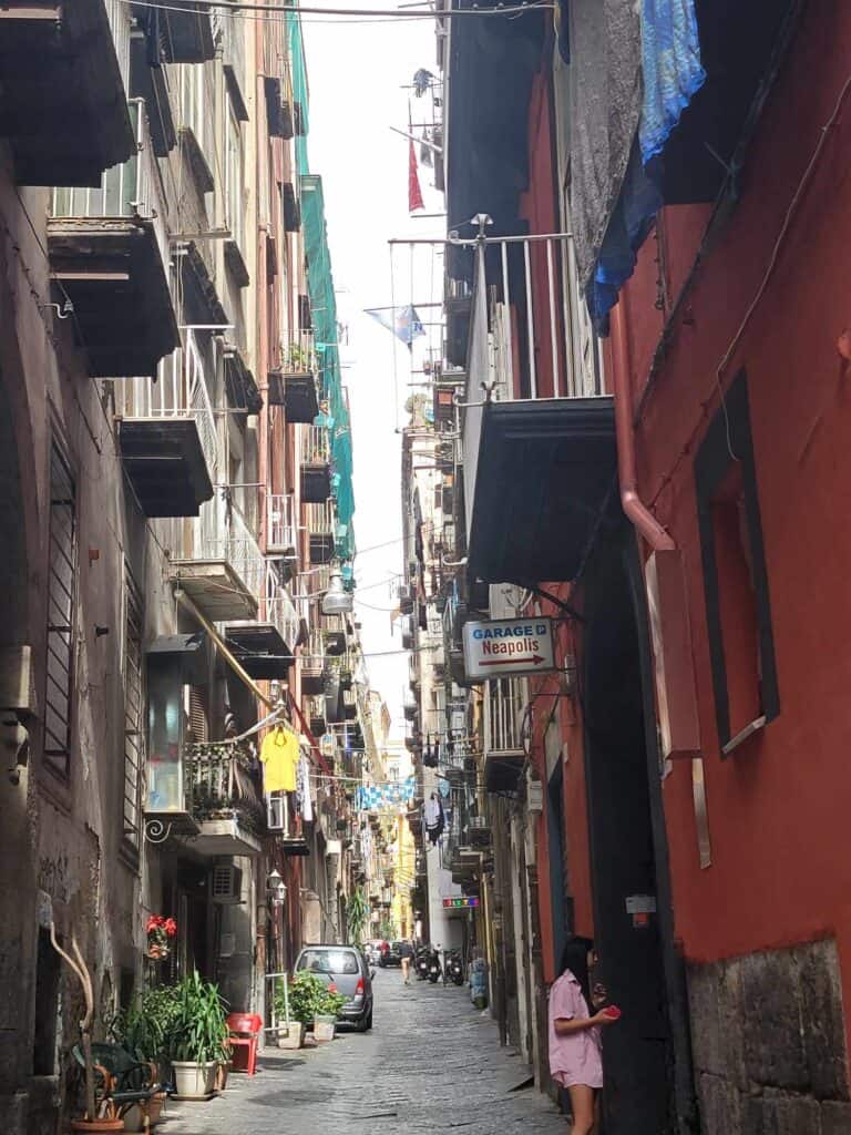 A very narrow street with a small sign with an arrow that says "Garage Neapolis"