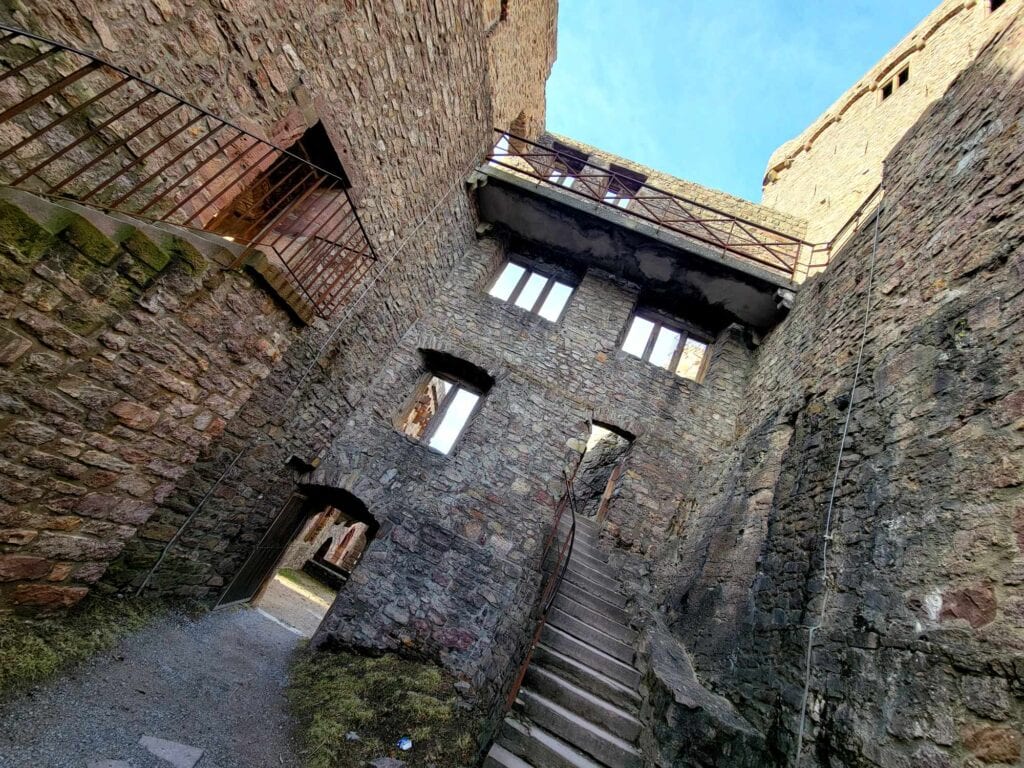 A stone building couryard with stairs with railings going this way and that