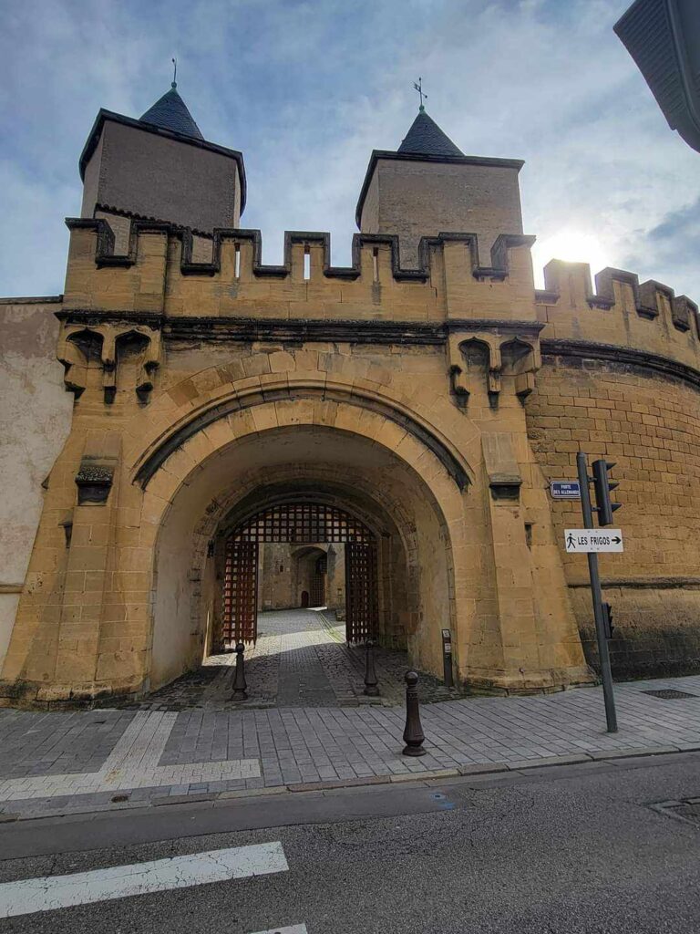 A stone building with an arched entrance gate and two square towers.