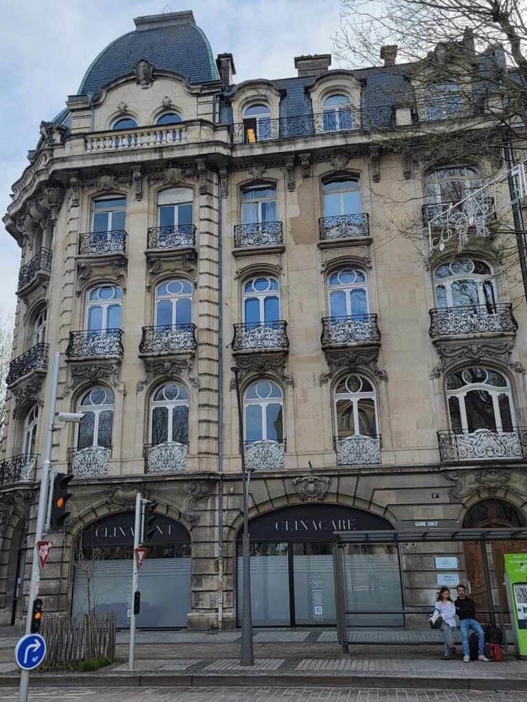 A large art nouveau building with rounded windows each with a small balcony surrounded by a metal grille