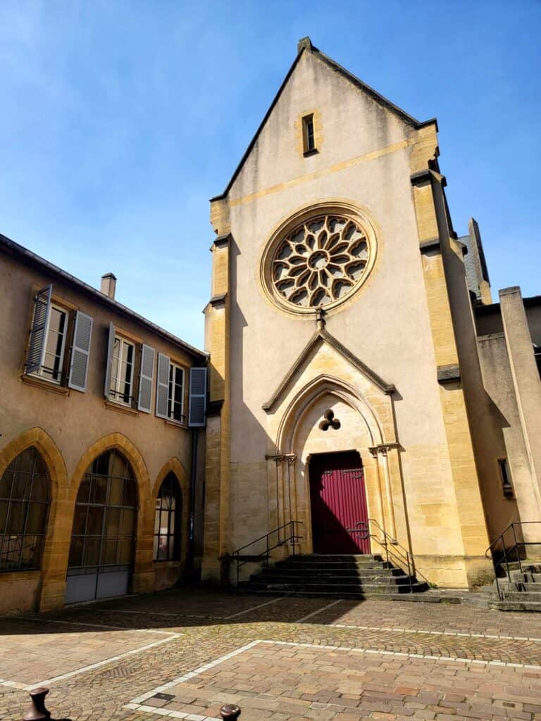 A small stone building with a red door and a rose window.