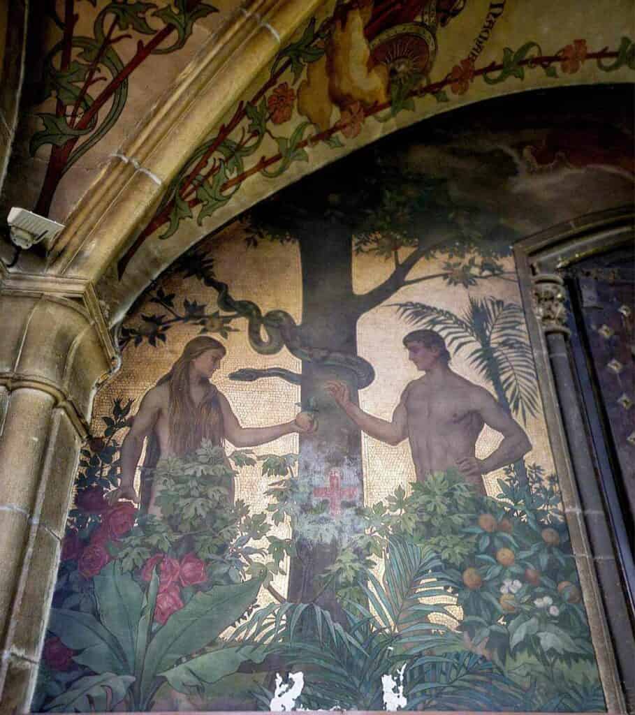 A mosaic of Adam and Eve standing on either side of a tree. Eve is giving Adam an apple as the serpent watches. Tropical plants in front and a background of gold tiles