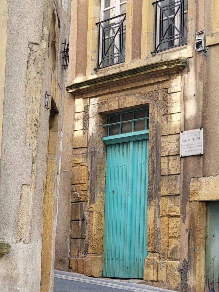 A yellow stone building with a bright turquoise door