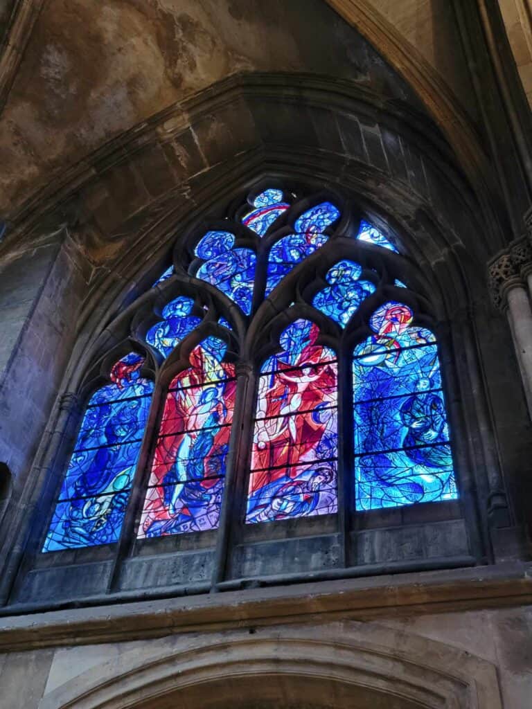 A blue and red stained glass window by Mark Chagall with scenes from the Old Testament