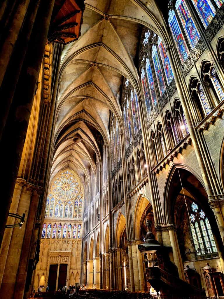 A soaring nave with gothic arches and a vaulted ceiling with a wall of stained glass windows