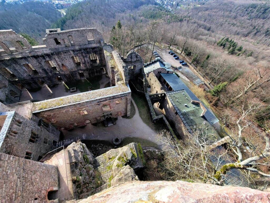 A birdseye view of a caslte ruin complex on the left with a small parking area to the right