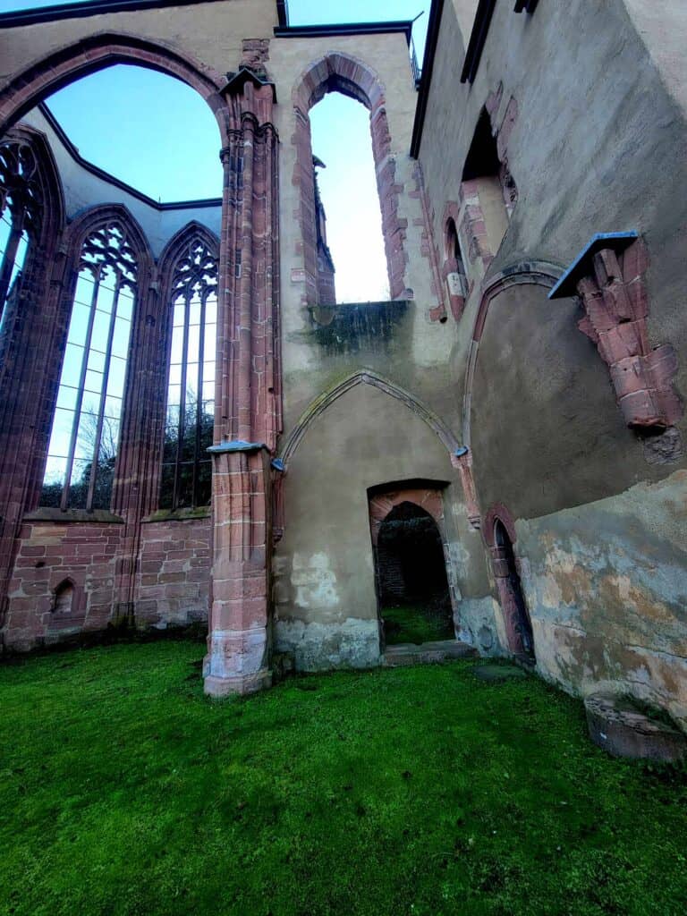 A skeletal ruin of a chapel with high sandstone arches coming out of a perfect green lawn