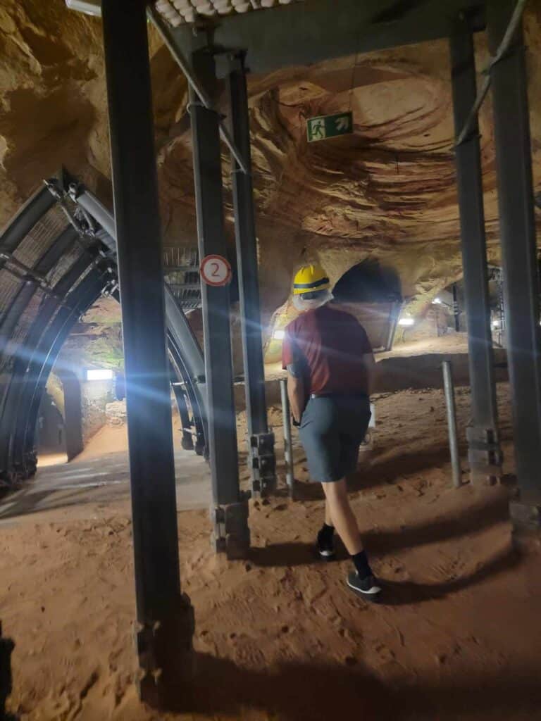 A man walks through a cave shored up by large steel beams