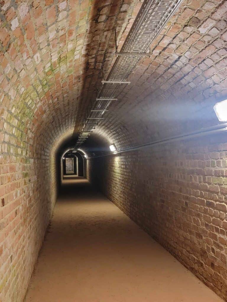 A symmetrical bricked archway with utility pipes overhead