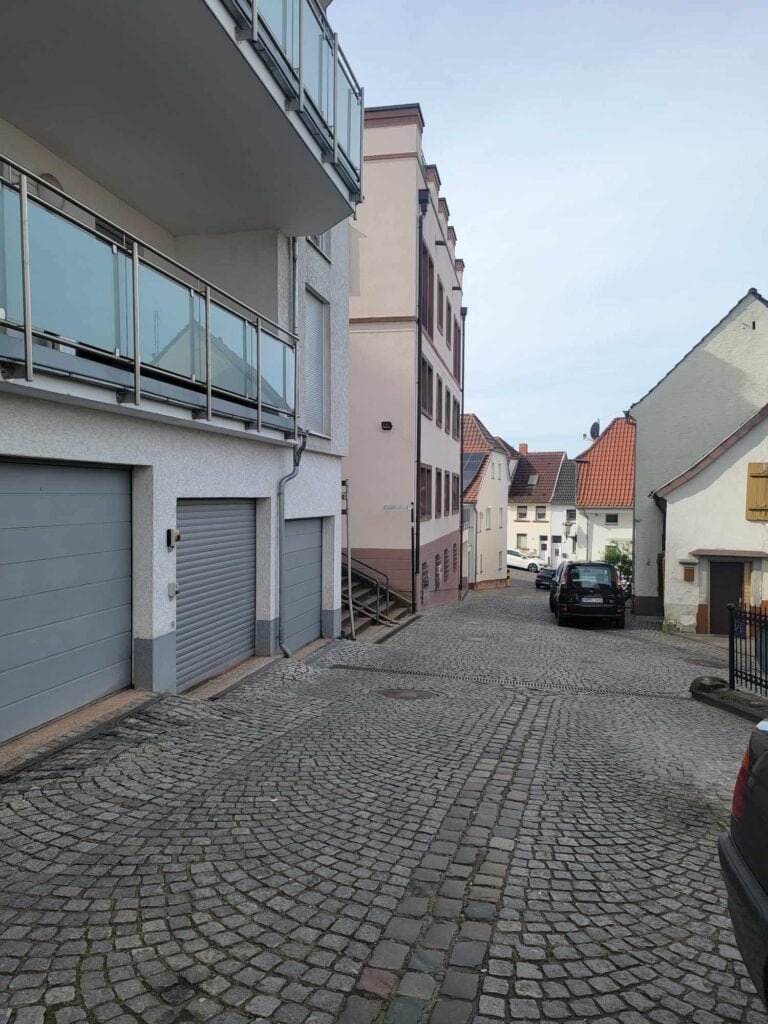 A cobblestone street with nondescript buildings on the left