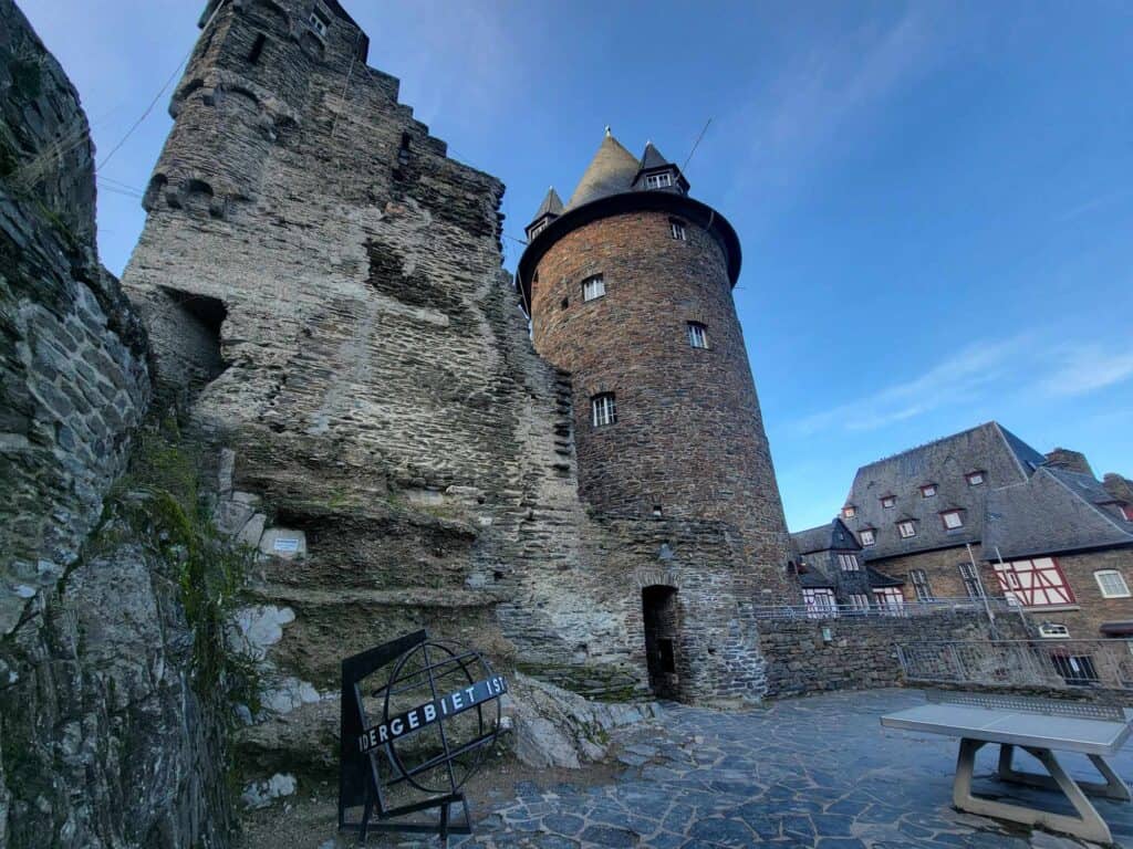 A rustic stone tower ruin on the left and a newer looking round tower with a conical roof