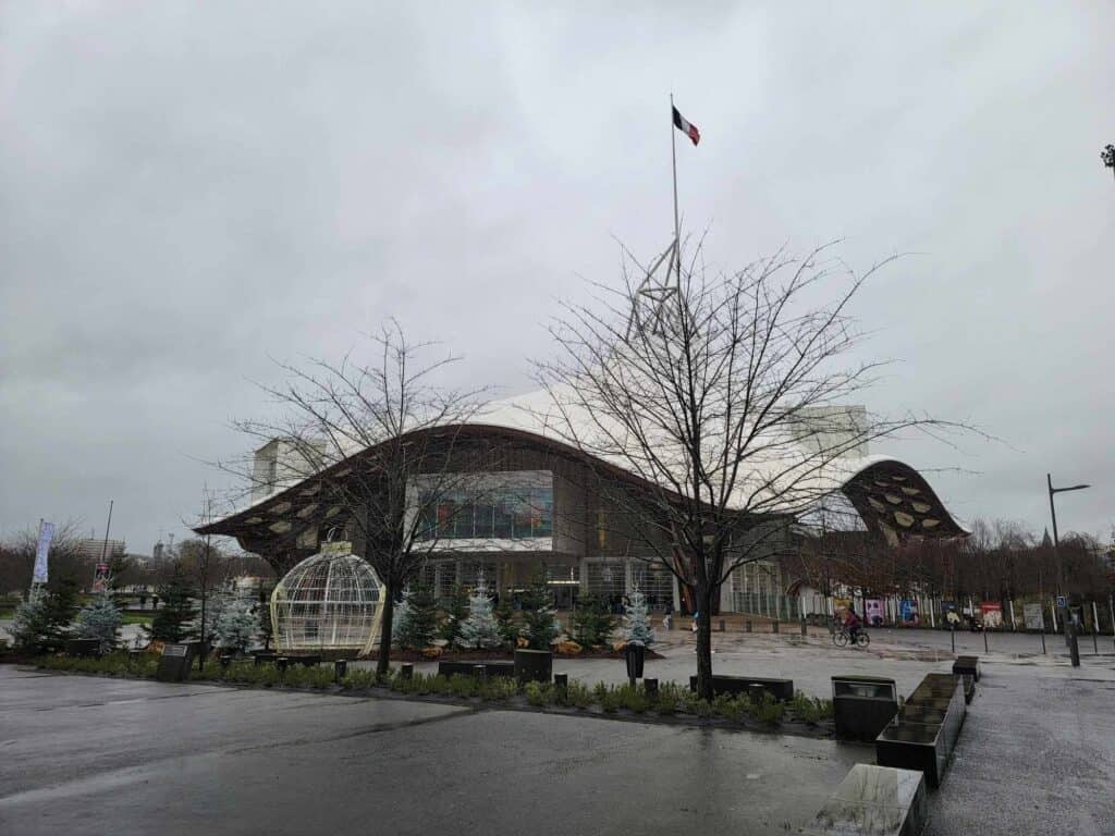 A building with a sloping wavy white roof and rows of windows