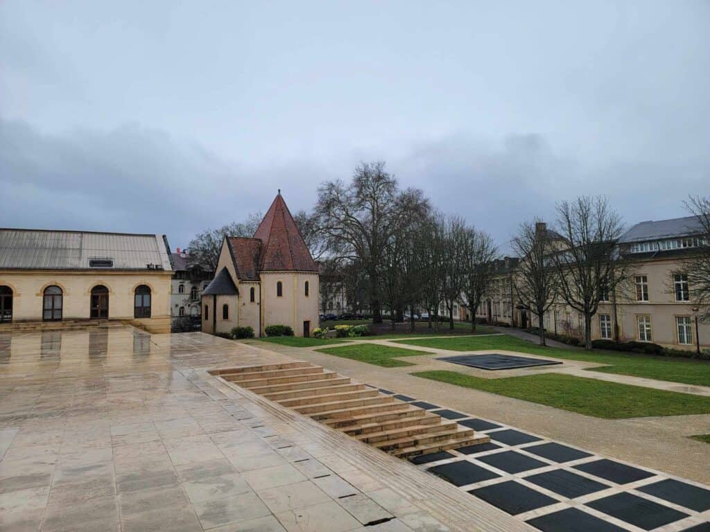 An open plaza with an 8-sided stone chapel with a tall pointed roof and several small windows