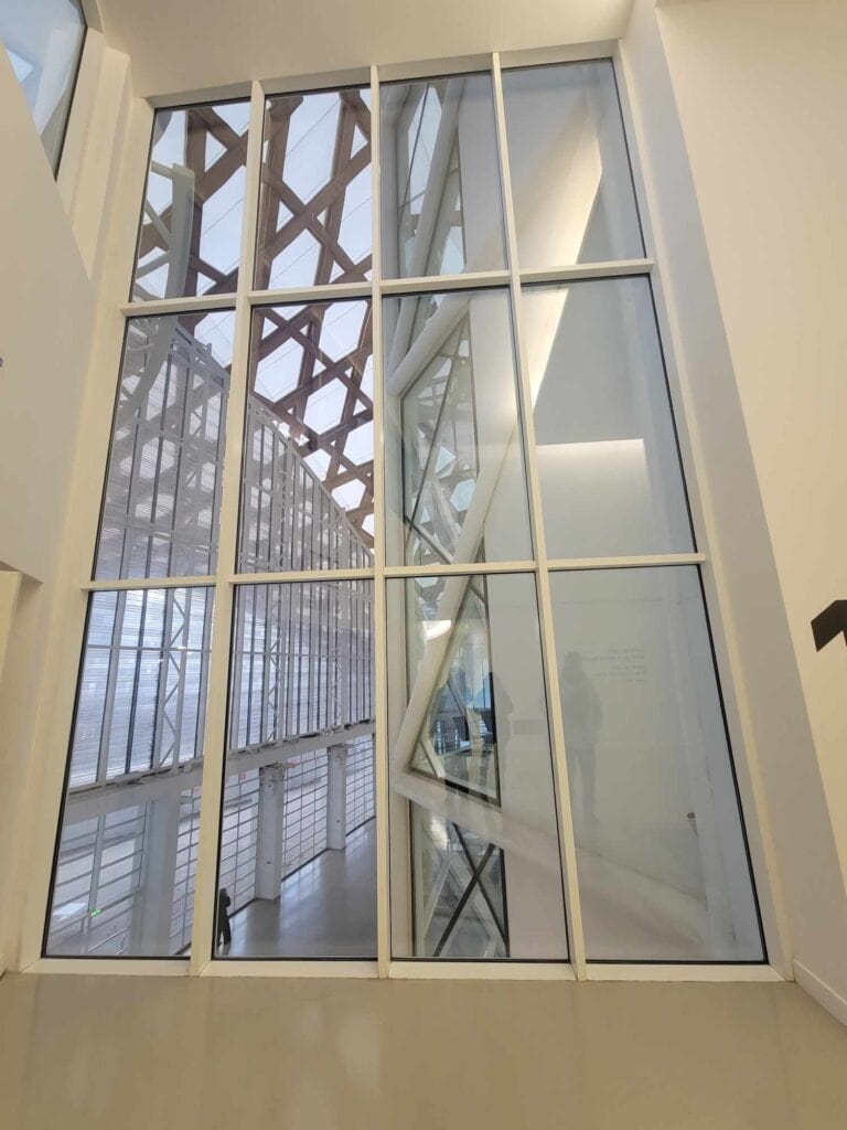 An interior of a white building with two stories of framed glass, very modern