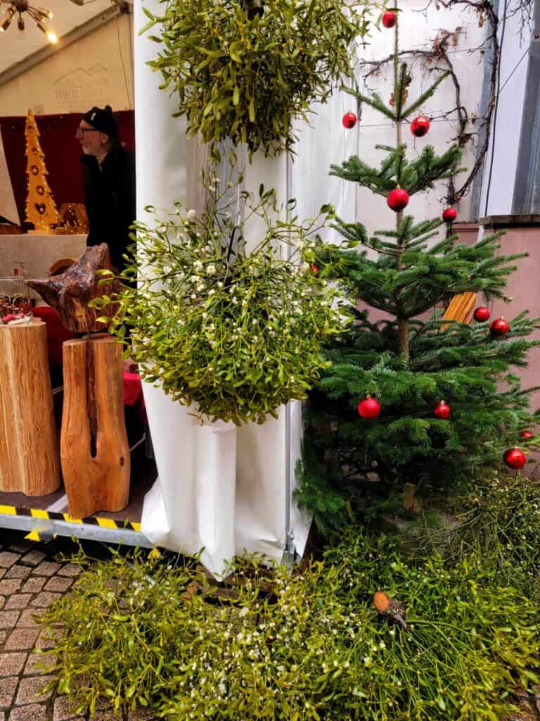 Huge clumps of lie mistletoe, a small evergreen with red ornaments, and a tented market stall selling wood crafts