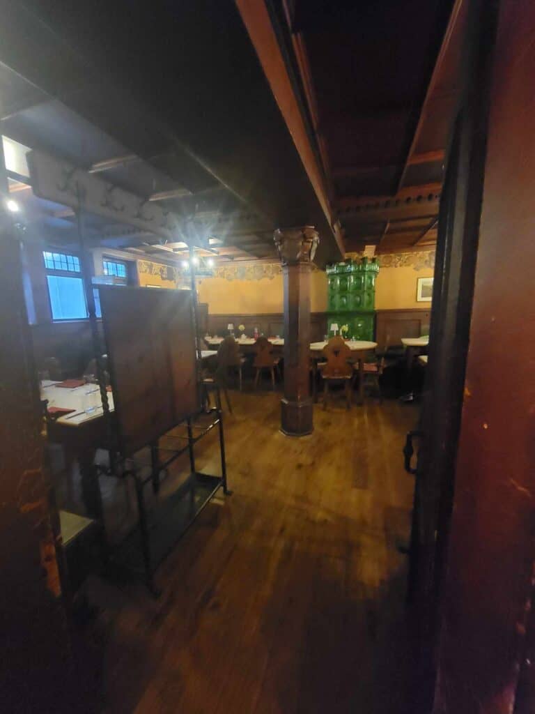 A cozy wooden room with beamed ceiling with dark wooden tables and chairs