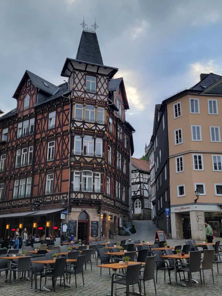 An elaborate half-timbered building with tables and chairs in the foreground